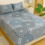 Blue pebble circle printed cotton bedsheet with matching pillow covers on wooden bed